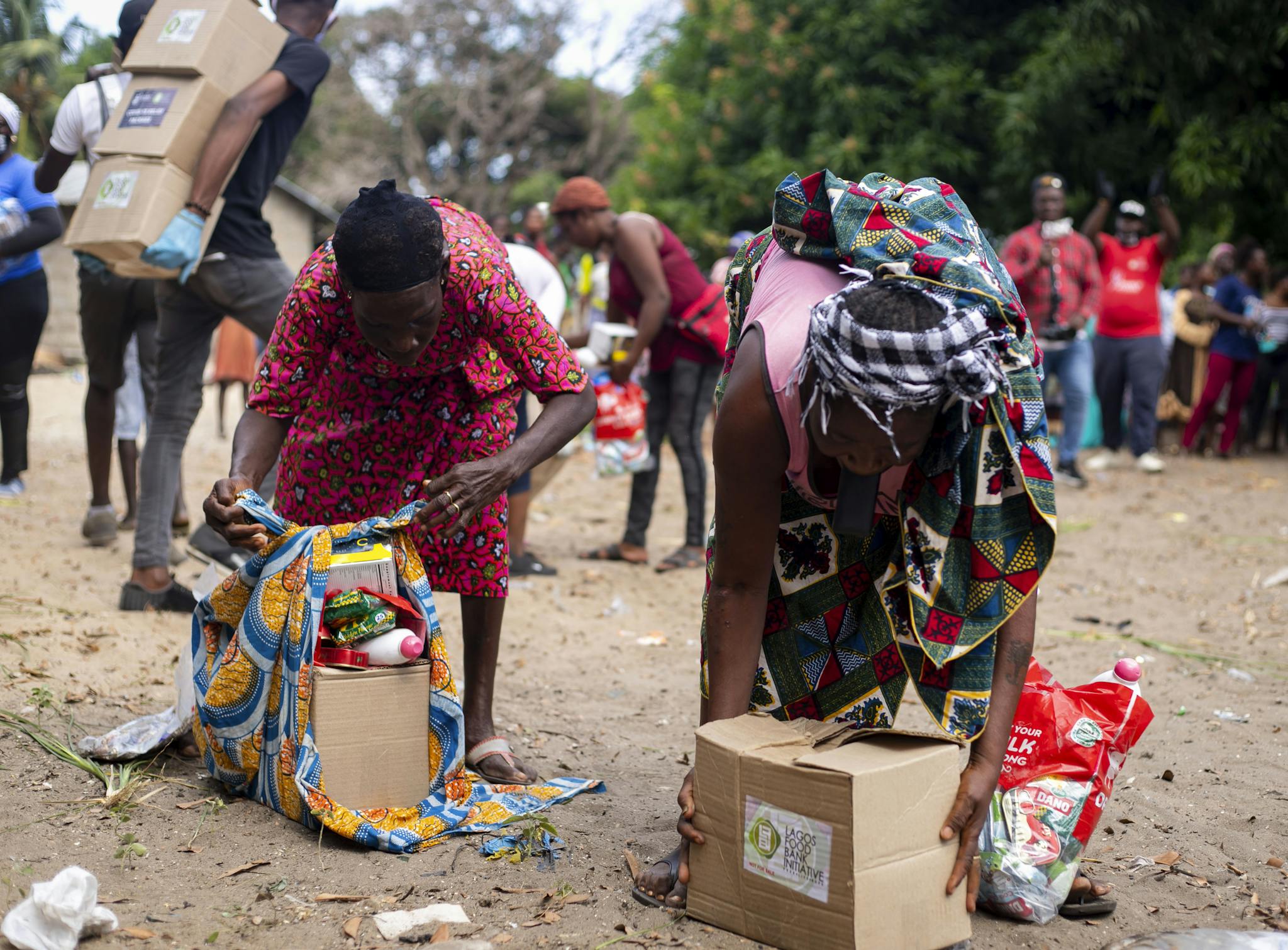 People collecting relief supplies in a community outdoor setting.
